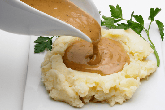 gravy boat pouring rich turkey gravy over mashed potatoes