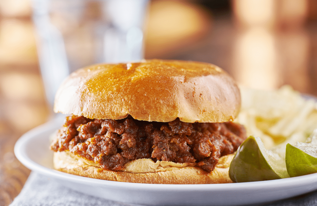 A plate with a Sloppy Joe on a brioche bun made with Sauce Goddess Big & Tangy Black Pepper sauce