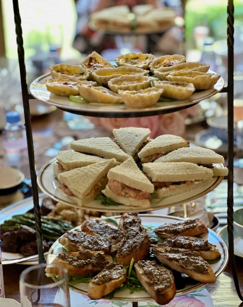 A decorated brunch table with a 3 tiered platter of small bites to solve how to host a brunch.